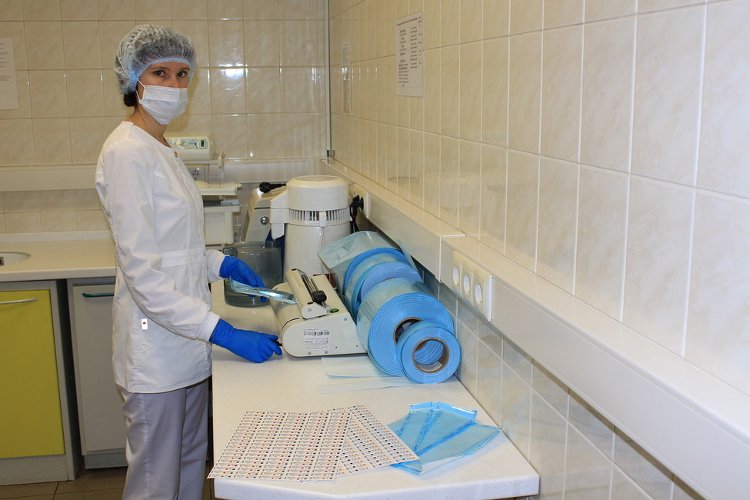 Стерилизационная медсестра запаковывает инструменты в упаковочную ленту для стерилизации в термосварочном аппарате